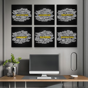 May include: Six black framed motivational word art prints with white text, including words like "Motivation," "Leadership," and "Success." The prints are arranged on a gray wall above a wooden desk with a computer monitor and decorative items.