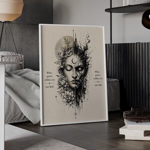 Op de afbeelding: Een ingelijste kunstdruk met een illustratie van een gespleten gezicht, met bloemen en een maan aan de ene kant en abstracte donkere inkttexturen aan de andere kant. De tekst luidt: What grows within you can heal. What grows within you can ruin.
