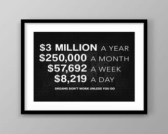 May include: A framed black and white print with text. The text includes financial goals: $3 million a year, $250,000 a month, $57,692 a week, and $8,219 a day. The bottom of the print reads, "Dreams don't work unless you do."