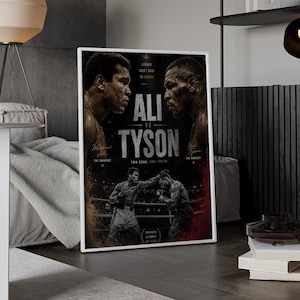 May include: A framed poster featuring a black and white graphic design of boxers Muhammad Ali and Mike Tyson. The text reads ALI VS TYSON, LEGENDS AREN'T BORN IN COMFORT, TWO ERAS. ONE TRUTH, and GREATNESS IS EARNED NOT GIVEN, with action imagery.