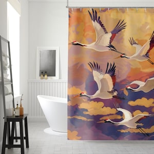 May include: A shower curtain featuring a colorful abstract background with five white cranes flying in formation. The cranes have black wing tips and red accents on their wings. The background is a mix of purple, orange, and yellow.
