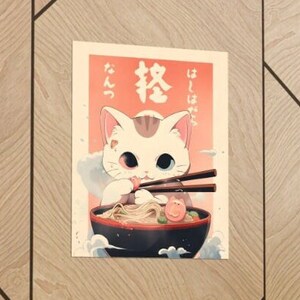May include: A white cat with one blue eye and one red eye is eating ramen noodles from a bowl with chopsticks. The Japanese text on the poster says "Itadakimasu" and "Ramen".