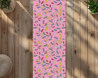 May include: A pink yoga mat with a colorful sprinkle pattern. The sprinkles are in various shapes and sizes, including long and short lines, circles, and ovals.