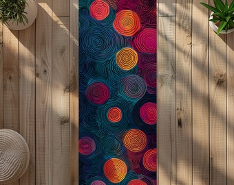 Puede incluir: Una esterilla de yoga con un diseño abstracto colorido que presenta círculos giratorios en tonos de rojo, naranja, amarillo, rosa y azul sobre un fondo azul oscuro.