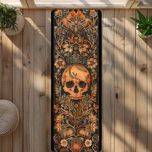 May include: A black yoga mat with a floral design and a skull in the center. The flowers are in shades of orange and yellow, and the skull is white with black details.