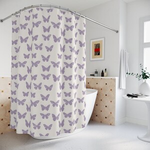 May include: A white shower curtain with a lavender butterfly pattern. The shower curtain is hung on a curved shower rod.