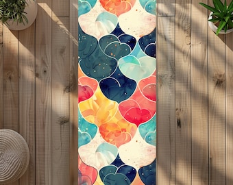 May include: A colorful yoga mat with a geometric pattern of overlapping hearts in shades of blue, red, yellow, and white. The mat has a textured surface and a subtle watercolor effect.