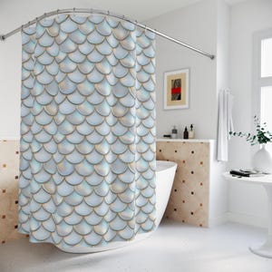 May include: A light blue shower curtain with a repeating pattern of overlapping, iridescent scales. The scales have a gold trim, creating a shimmering effect. The curtain is hanging in a bathroom with a white tub and a curved shower rod.