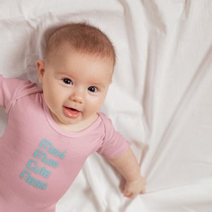Puede incluir: Un body rosa para bebé con las palabras "Max Mum Cute Ness" en letras azul claro.