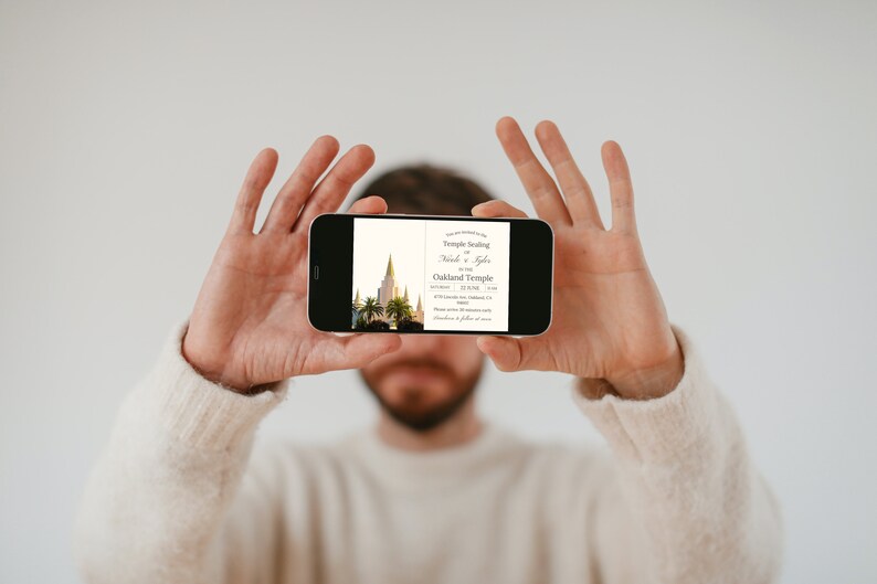 K&ouml;nnte beinhalten: Eine Person h&auml;lt ein Smartphone, auf dem eine Hochzeitseinladung mit einem Foto eines Tempels und dem Text "Temple Sealing Nick & Kayla Oakland Temple" zu sehen ist.