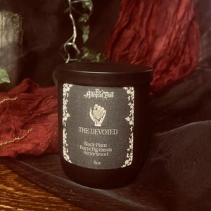 Puede incluir: Un tarro de vela negro con una etiqueta que dice "The Devoted". La etiqueta presenta un diseño de mano sosteniendo un corazón y las notas de fragancia: Ciruela negra, Higo quemado, Cassis y Madera de cedro. La vela es de 227g.