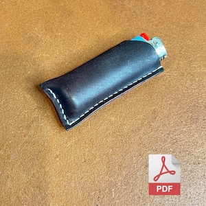 May include: A dark brown leather lighter case with white stitching. The case holds a lighter with a red button and blue top. The case is on a brown surface.
