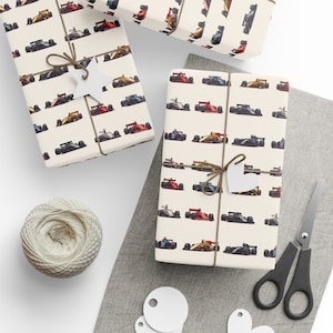 May include: A sheet of wrapping paper with a repeating pattern of colourful racing cars. The paper is cream coloured with a subtle texture. The cars are in various colours, including red, yellow, blue, and black.