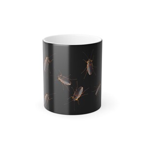 Pode incluir: Uma caneca de café de cerâmica preta com um padrão repetido de ilustrações detalhadas de baratas. Os insetos são marrons com detalhes em laranja e antenas longas. A caneca tem interior branco e acabamento brilhante.