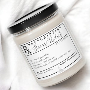 Könnte beinhalten: Ein weißes Glas-Kerzengefäß mit schwarzem Deckel. Das Etikett lautet "Prescription Stress Relief" mit der RX-Nummer "123RELAX". Die Kerze ist mit Sojawachs parfümiert und trägt ein Etikett mit der Aufschrift "Issued By: ca le scent".