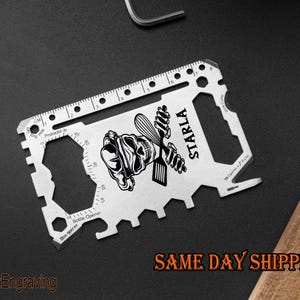 May include: A silver multi-tool credit card sized tool with a ruler, bottle opener, and other tools. The tool is engraved with a skull and crossbones design and the name "Starla".