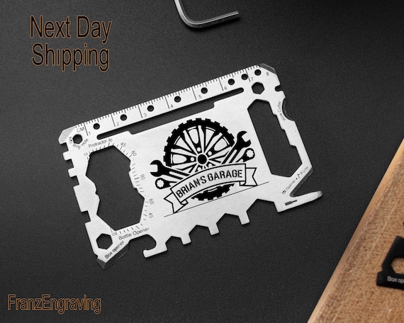 A credit-card-slim stainless steel multi-tool laser-engraved with a custom name/title — 'Brian's Garage' energy is peak dad-gift done right.