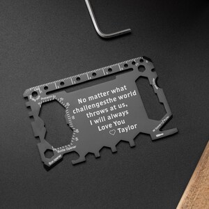 May include: A black multi-tool credit card sized tool with a ruler, bottle opener, and other tools. The tool has an engraved message that reads "No matter what challenges the world throws at us, I will always Love You Taylor".