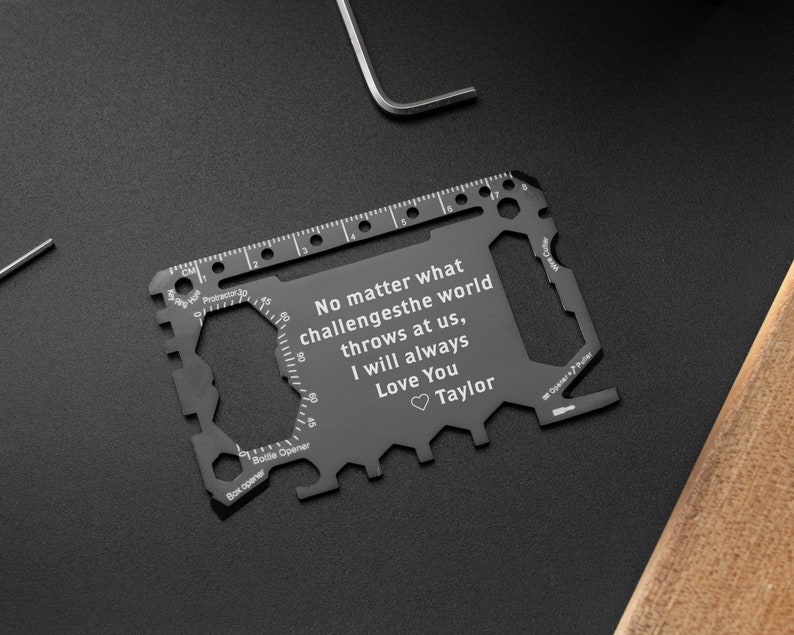 May include: A black multi-tool credit card sized tool with a ruler, bottle opener, and other tools. The tool has an engraved message that reads "No matter what challenges the world throws at us, I will always Love You Taylor".
