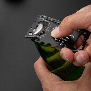 May include: Black multi-tool with a bottle opener, ruler, and a personalized message that reads "To us, world always Love You Taylor".
