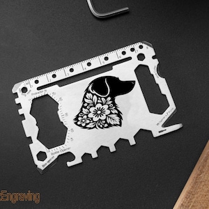 Könnte beinhalten: Eine silberne Multi-Tool-Karte mit einer Hunde-Silhouette und floralem Design. Mit Lineal, Winkelmesser und Flaschenöffner. Der Text "FranzEngraving" befindet sich unten links.