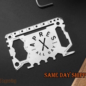May include: A silver multi-tool with a ruler, bottle opener, and other tools. The tool has the text "All Day's Pre" engraved on it.