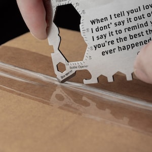 May include: A silver multi-tool with a box opener, bottle opener, and ruler. The tool has a quote engraved on it that reads: "When I tell you I love you I don't say it out of habit I say it to remind you that you're the best thing ever happened".