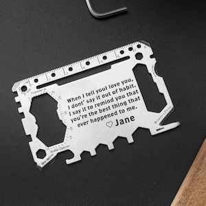 May include: A silver multi-tool credit card with a ruler, bottle opener, and other tools. The card has an engraved message that reads: "When I tell you I love you, I don't say it out of habit. I say it to remind you that you're the best thing that ever happened to me." The message is signed "Jane".
