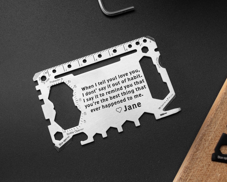 May include: A silver multi-tool credit card with a ruler, bottle opener, and other tools. The card has an engraved message that reads: "When I tell you I love you, I don't say it out of habit. I say it to remind you that you're the best thing that ever happened to me." The message is signed "Jane".