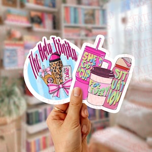 May include: Two die-cut vinyl stickers. The circular sticker features a leopard print tumbler, a coffee cup, and a Diet Coke can with the text The Holy Trinity and a pink bow. The second sticker shows a pink tumbler and coffee cup with text.