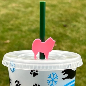 May include: A pink dog silhouette straw topper for a clear plastic cup with a snowflake and paw print design.