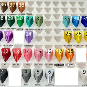 May include: A chart of 38 different colors of plastic filament for 3D printing. The colors are arranged in rows and columns, with each color labeled with a number and a name. The colors include black, white, red, green, blue, purple, orange, yellow, pink, brown, and silver.