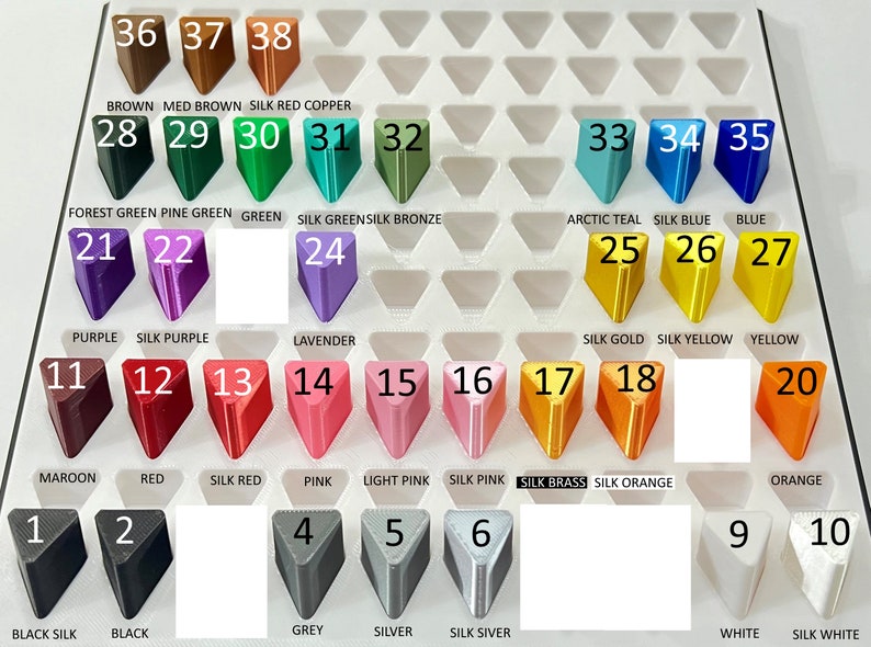 May include: A chart of 38 different colors of plastic filament for 3D printing. The colors are arranged in rows and columns, with each color labeled with a number and a name. The colors include black, white, red, green, blue, purple, orange, yellow, pink, brown, and silver.