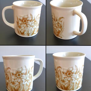 May include: A white ceramic mug with a black handle and the text "But First, Coffee" in a bold, black font. The mug is set against a neutral background, highlighting its simple design.