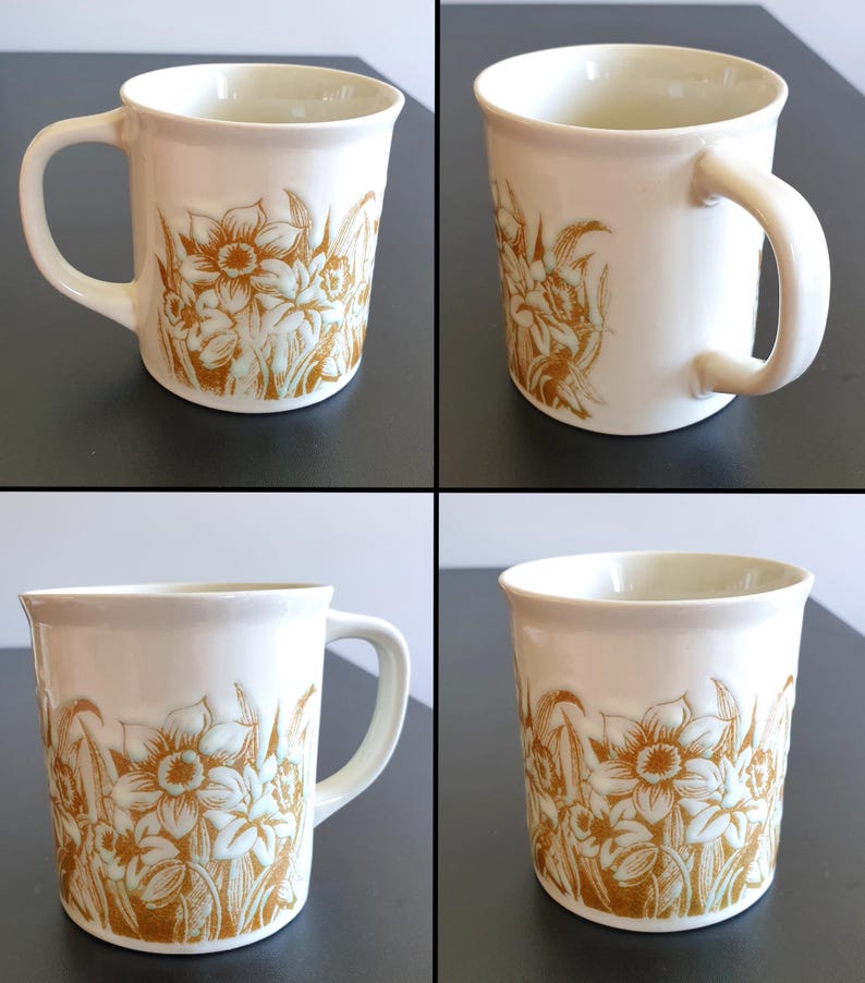 May include: A white ceramic mug with a black handle and the text "But First, Coffee" in a bold, black font. The mug is set against a neutral background, highlighting its simple design.