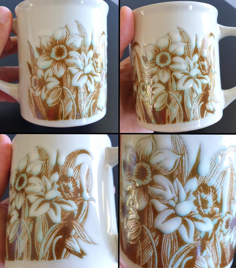 May include: White ceramic mug featuring a floral design in shades of brown and light blue. The flowers and leaves are embossed on the mug's surface. The mug has a curved handle and a slightly flared rim.