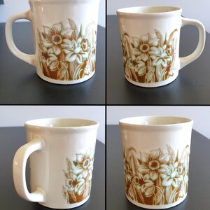 May include: A white ceramic mug with a black handle and the text "But First, Coffee" in a black, handwritten-style font. The mug is on a white surface.