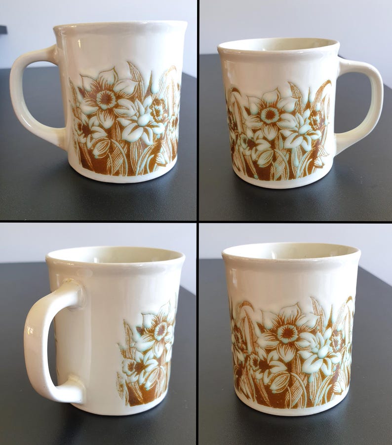 May include: A white ceramic mug with a black handle and the text "But First, Coffee" in a black, handwritten-style font. The mug is on a white surface.