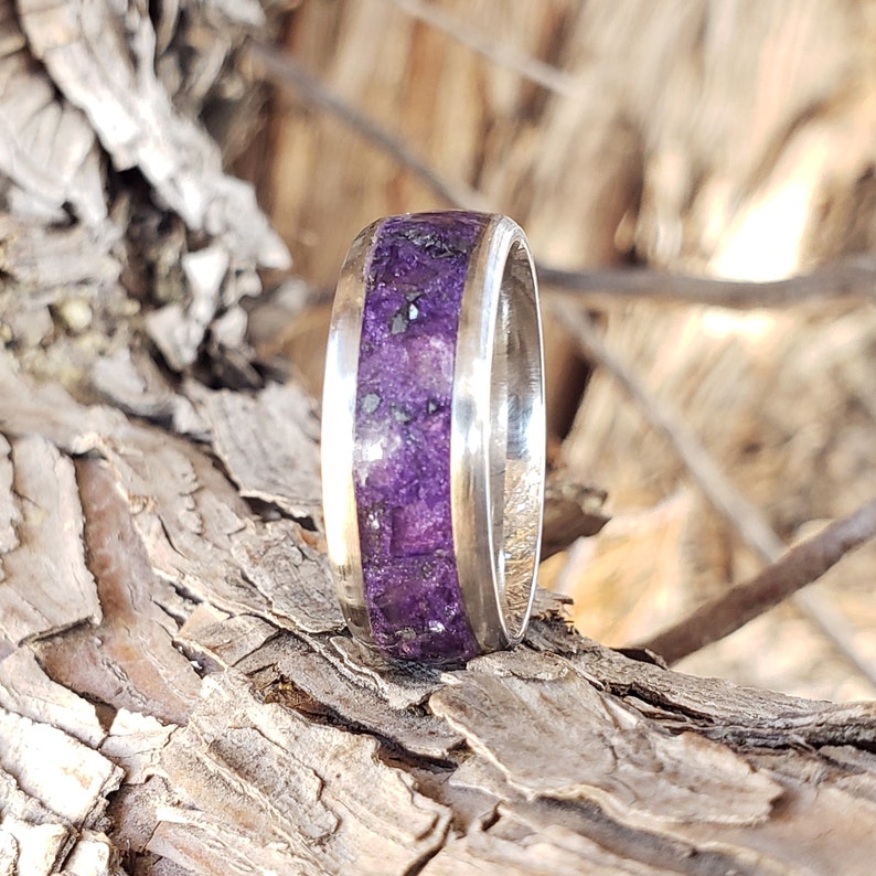 May include: A silver ring with a purple and black inlay. The ring is made of metal and has a polished finish.