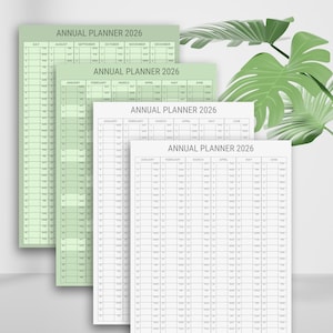 Könnte beinhalten: Vier Jahresplaner für 2026 sind gestapelt, die oberen drei in Grüntönen und der untere in Weiß. Jeder Planer zeigt ein Jahreskalender-Layout mit dem Text "ANNUAL PLANNER 2026".