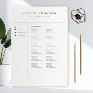 May include: A minimalist resume template with the name "KINSLEY JOHNSON" at the top, followed by "PROFESSIONAL POSITION." The document includes sections for contact information and references. Two pencils and a geometric candle holder are also visible.