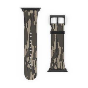 May include: A camouflage pattern watch band in shades of green, brown, and tan. The band has a black buckle and connectors. The band is shown in two pieces, with the holes for the watch pins visible.