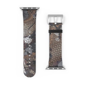 May include: A patterned Apple Watch band in shades of brown, gray, and white. The band features a camouflage-like design with a silver buckle and connectors. The watch band is shown in two pieces, with the band laid out flat.