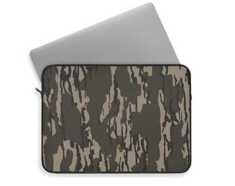 May include: A laptop computer rests inside a camouflage-patterned laptop sleeve. The sleeve features a black border and a zipper closure. The camouflage design incorporates shades of green, brown, and tan, creating a textured appearance.