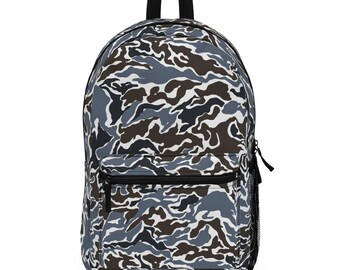 May include: A backpack with a camouflage pattern in shades of gray, brown, and white. The backpack has a front zippered pocket, a side mesh pocket, and a black handle. The bag is designed for carrying books, laptops, or other essentials.