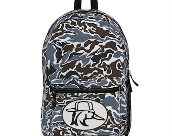 May include: A camouflage-patterned backpack in shades of blue, brown, and white. The backpack features a black top handle, a front zippered pocket, and a side mesh pocket. A white oval patch with a duck wearing a hat is on the front.
