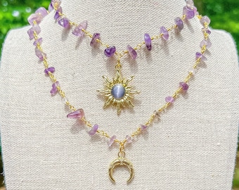 Puede incluir: Un collar de dos capas con un colgante de sol y luna creciente de oro. El collar está hecho con pequeñas piedras de amatista púrpura y una cadena de oro.