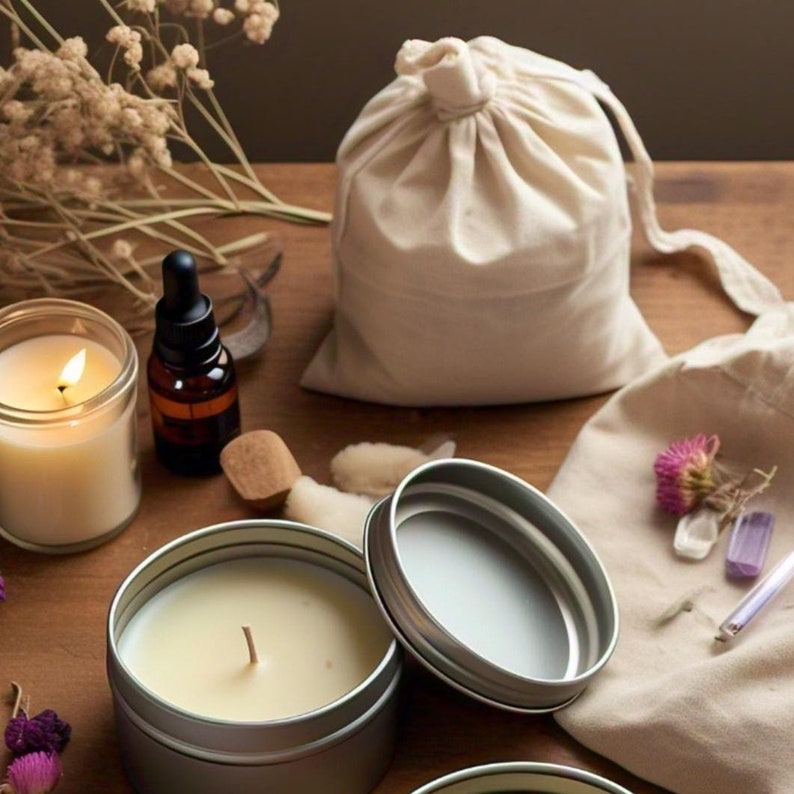 Pu&ograve; includere: Un set di prodotti naturali per la casa che include una borsa di cotone bianco con coulisse, due barattoli di candela argentati, una bottiglia di vetro di olio essenziale e un blocco di legno. Gli articoli sono disposti su una superficie di legno con un panno bianco e cristalli.