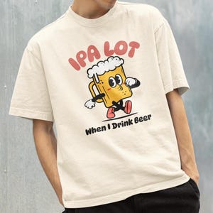 May include: A cream-coloured t-shirt featuring the text "IPA LOT" in red, above a cartoon beer mug with a white foamy top, black arms and legs, and red shoes. The text "When I Drink Beer" is below the beer mug.