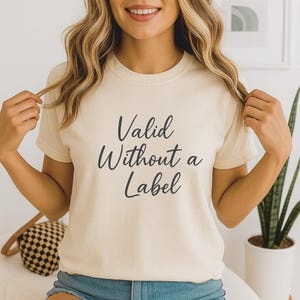 May include: Cream-colored t-shirt with the text "Valid Without a Label" in black script. The shirt is short-sleeved and appears to be made of a soft material. The overall style is casual and comfortable.